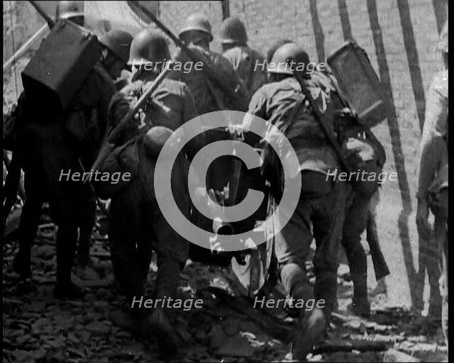 A Group of Male Japanese Soldiers Pushing a Gun Over Rubble in a Street in Shanghai, 1937. Creator: British Pathe Ltd.