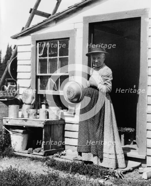 Elderly woman, standing at doorway, on Mackinac Island, Michigan, 1903. Creator: Frances Benjamin Johnston.