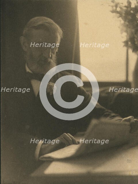 Bearded man in spectacles reading a newspaper, c1900. Creator: Anne K Pilsbury.