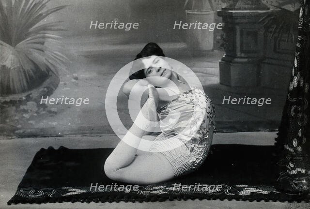 A Bulgarian female acrobat performing contortions in a photographic studio, between 1890 and 1910. Creator: Unknown.