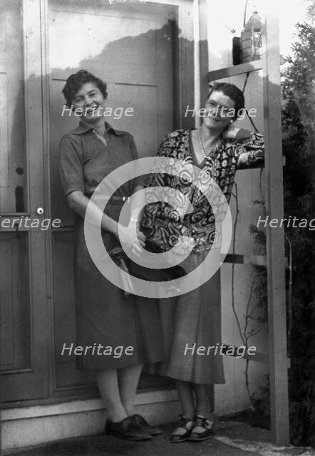 Mrs. Mary Benson and Alice DeLamar, standing by the door of a house, 1933. Creator: Arnold Genthe.