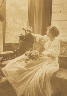 Young woman seated by a window with flowers in her lap, c1900. Creator: Mary A. Bartlett.