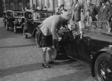 Kitty Brunell in her Aston Martin, chatting to a man in Highland dress, RSAC Scottish Rally, 1933. Artist: Bill Brunell.