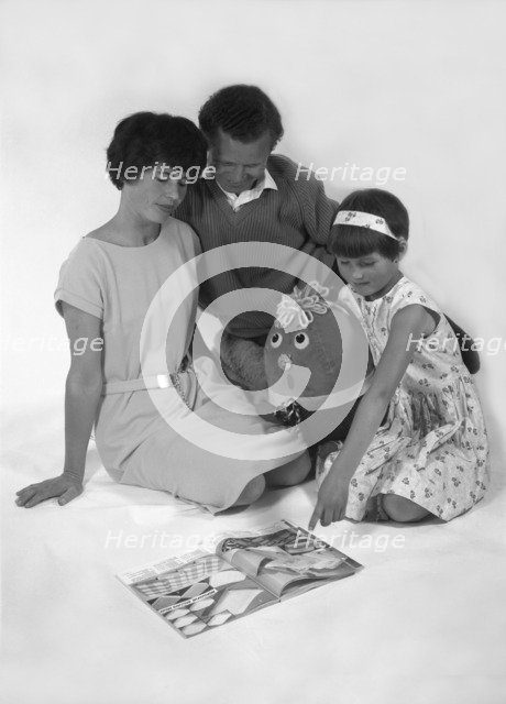 Family group looking at a magazine, 1963. Artist: Michael Walters