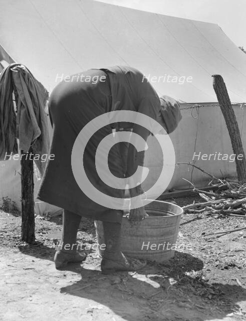 A grandmother washing clothes in a migrant camp, Stanislaus County, California, 1939. Creator: Dorothea Lange.