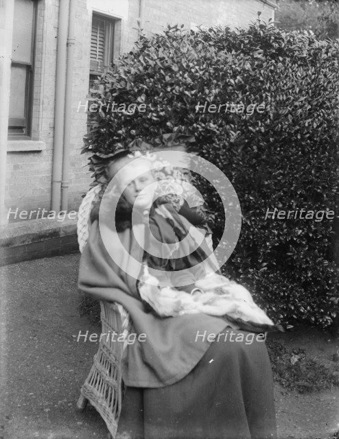 Woman sitting in a chair in a garden, c1900. Creator: Kirk & Sons of Cowes.