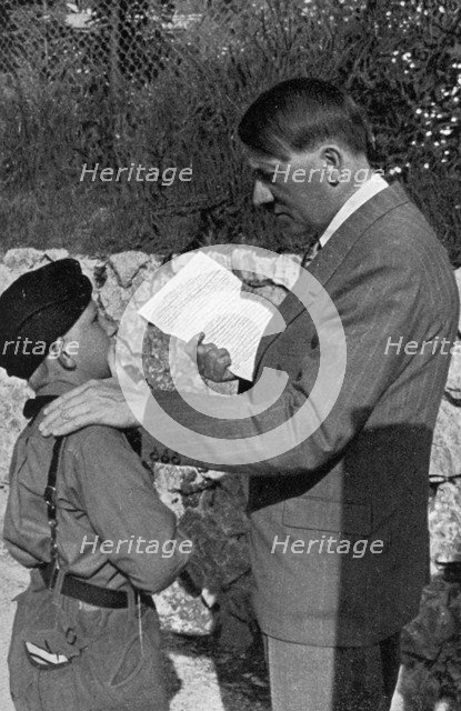 A young boy from the Hitler Youth shows Adolf Hitler a letter from his sick mother, 1936. Artist: Unknown