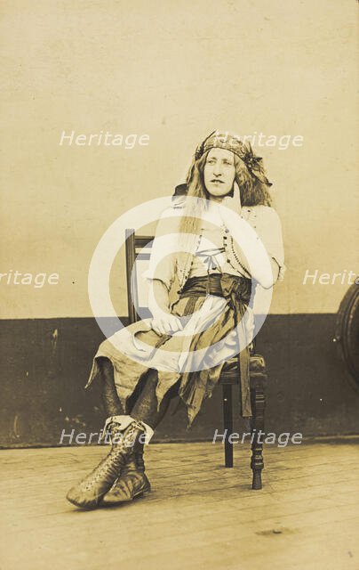 A man in drag sits pensively on a chair, on the deck of a ship, (between 1910 and 1919?). Creator: Unknown.