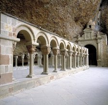 View of the arches and geminated columns of the cloister by the rocks of the Benedictine monaster…