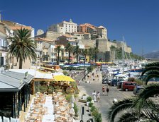 Restaurants in the old port with the Citadel in the background, Calvi, Corsica.
