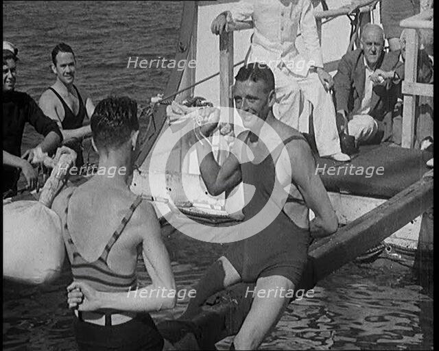 Two Male Civilians in Swim Suits Sitting on a Pole and Enjoying a Pillow Fight in Front..., 1931. Creator: British Pathe Ltd.