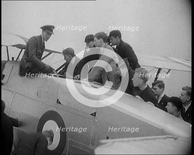 An RAF Officer Showing a Group of Male Children His Aeroplane, 1931. Creator: British Pathe Ltd.