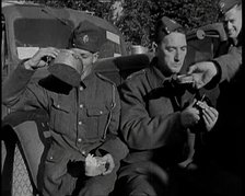 Two Male British Soldiers Sitting at  the Front of Army Trucks and Eating While Two Others..., 1939. Creator: British Pathe Ltd.