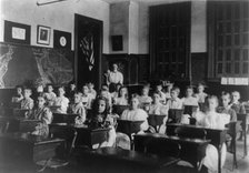 Grade school children posed in classroom, with teacher standing in back..., Washington DC, (1899?). Creator: Frances Benjamin Johnston.