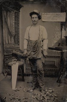 Carpenter or Cabinetmaker Standing Before a Sign Advertising His Trade, 1860s-80s. Creator: Unknown.