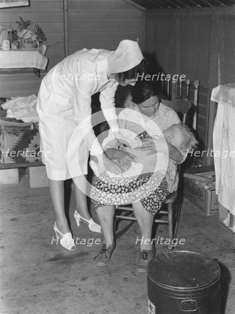 Nurse attending sick baby, FSA camp, Farmersville, Tulare County, California, 1939. Creator: Dorothea Lange.