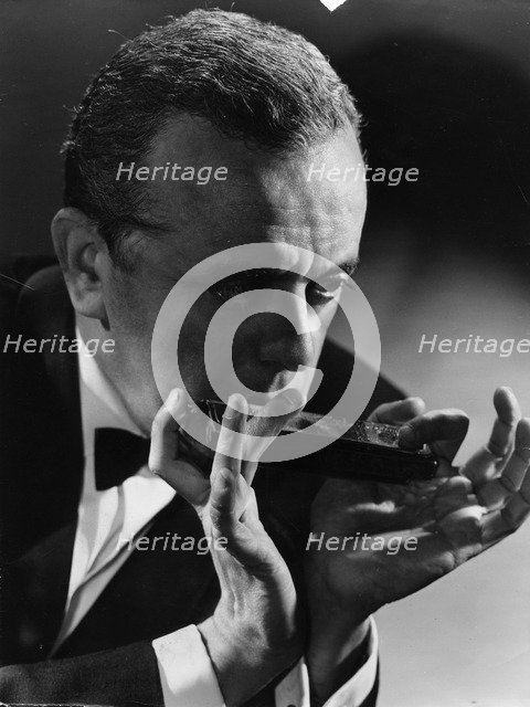 Larry Adler (1914-2001), Musician, playing his harmonica, c1940s. Artist: Unknown