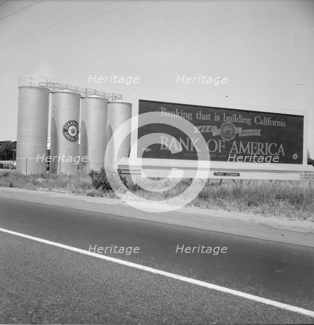 Highway gas tanks and signboard approaching town, between Tulare and Fresno on U.S. 99, 1939. Creator: Dorothea Lange.