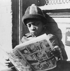 Negro youth reading a funny paper on a door step in the Southwest section, Washington, D.C., 1942. Creator: Gordon Parks.
