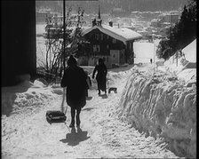 A Group of Female Civilians Skiing down a Snowy Hill with a Picturesque Alpine Village..., 1920. Creator: British Pathe Ltd.