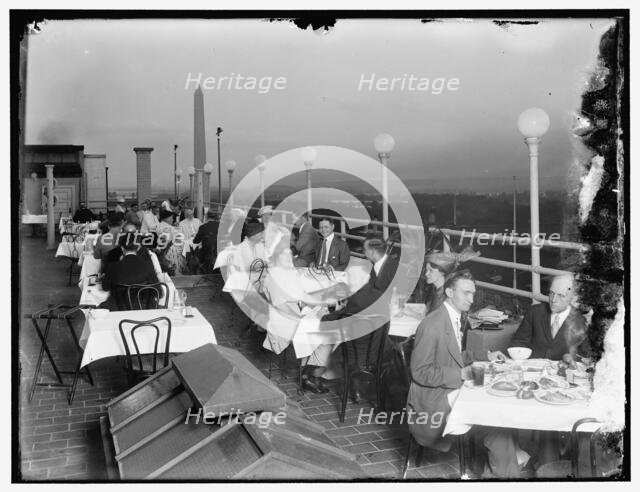 Dining on rooftop; Washington monument in background, between 1910 and 1920. Creator: Harris & Ewing.